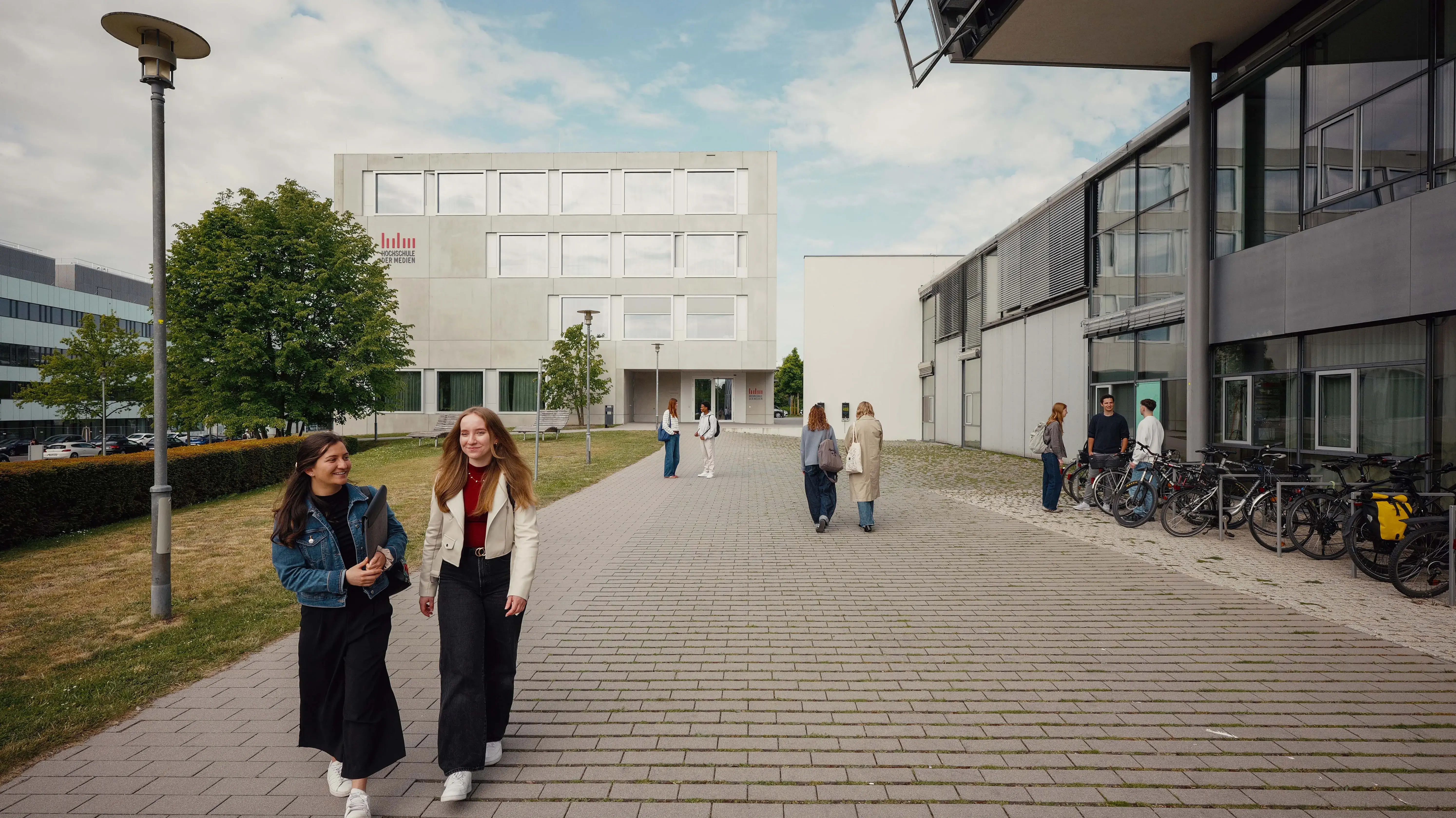 Studierende unterhalten sich beim Verlassen der Hochschule der Medien.