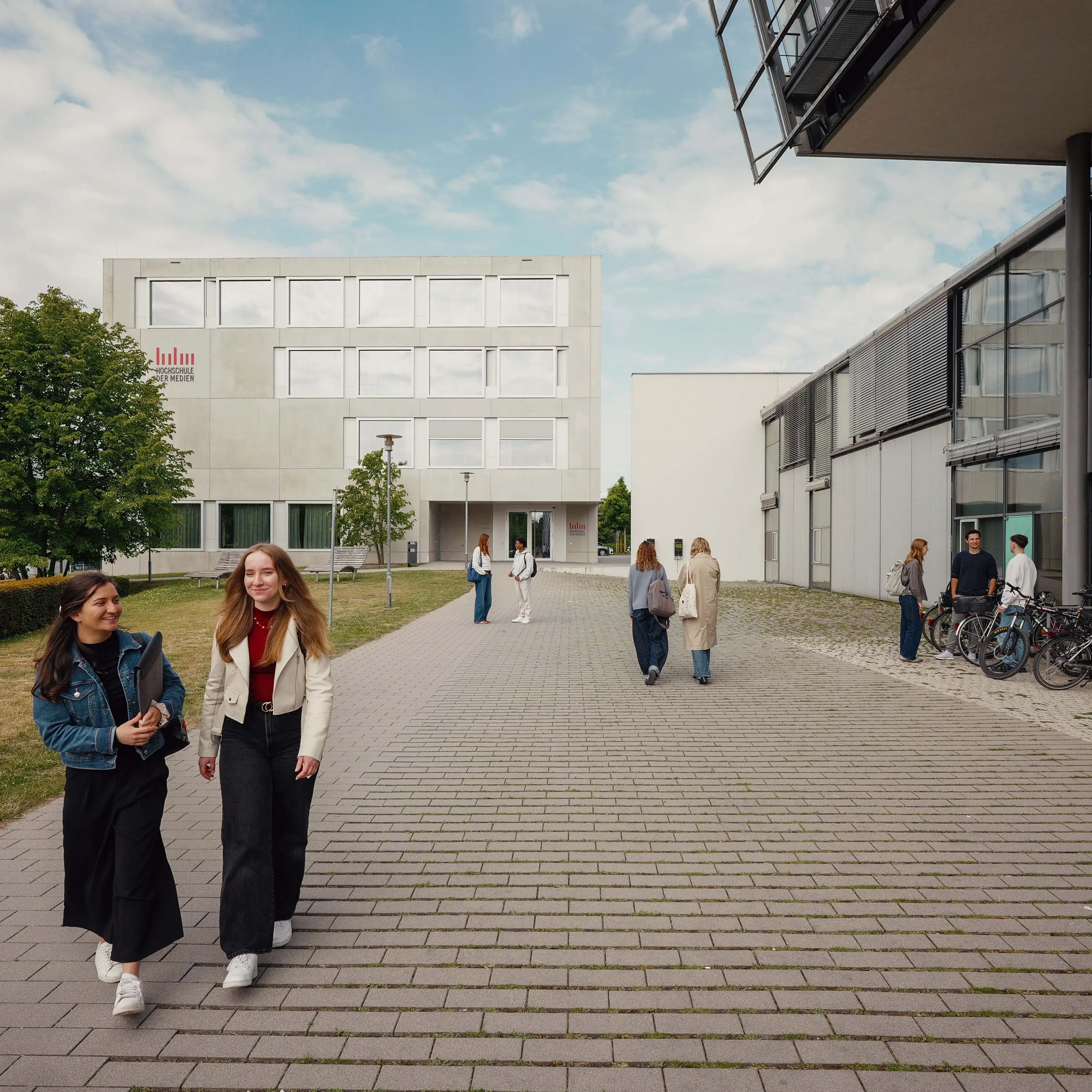 Studierende unterhalten sich beim Verlassen der Hochschule der Medien.